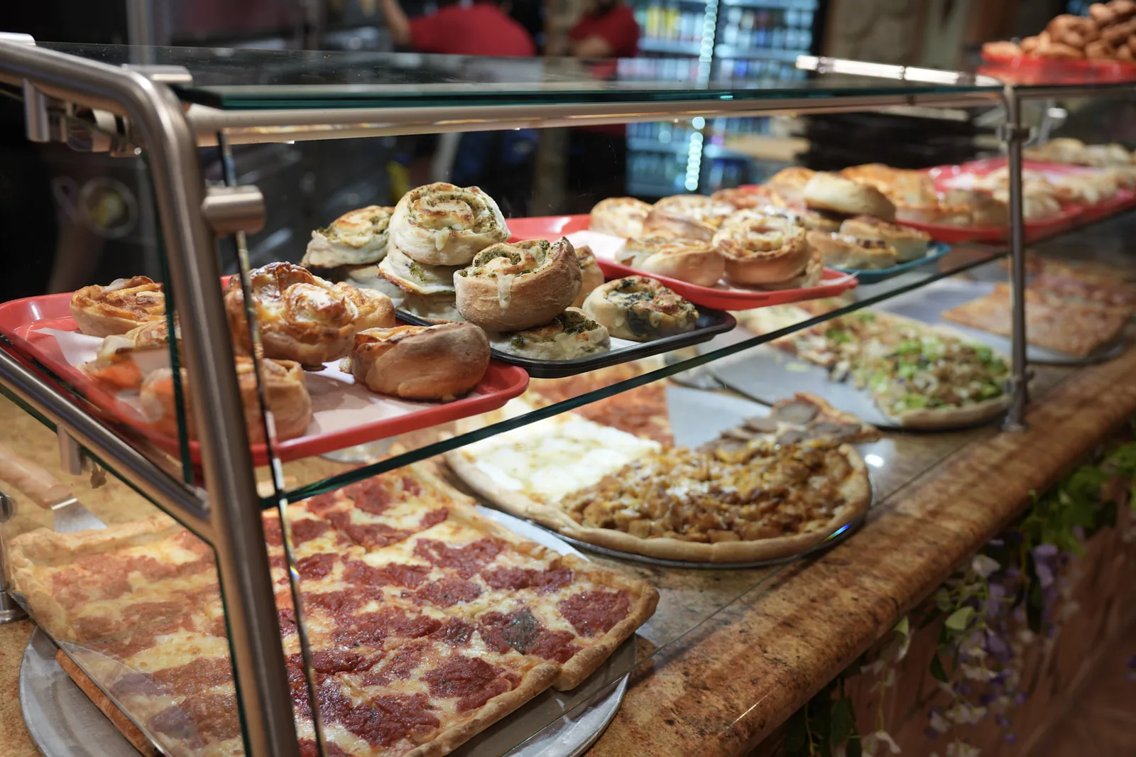 Fresh pizza slices and specialty rolls in the display case at Ciminelli's in Bethpage